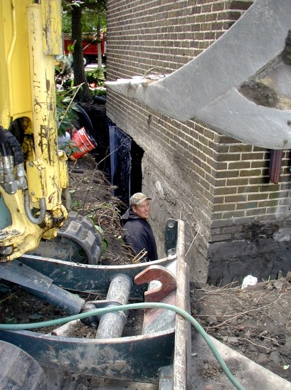 Plastic film adheres to trowled mastic. Here, Tom, Jr., helps install plastic sheet to wall