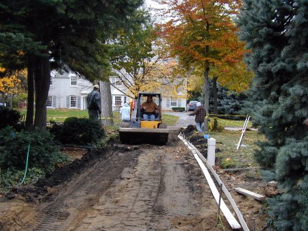 Drain to city storm sewer is buried, leaving cleanout exposed where it turns to run along side of drive.