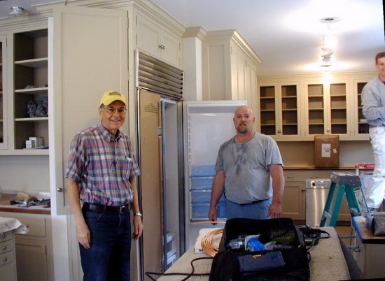 Richard Holton installs fridge while Rob works on window trim